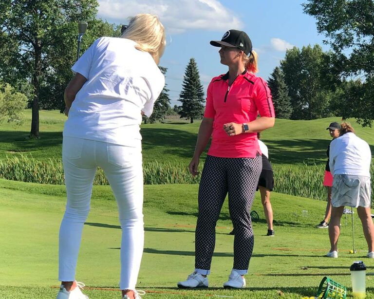 Golf coach Anna Young helping beginner golfer's swing